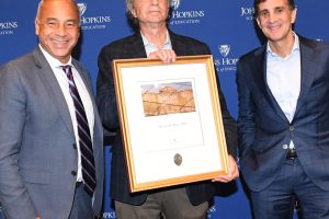 Three people standing next to each other and one person is holding an award.