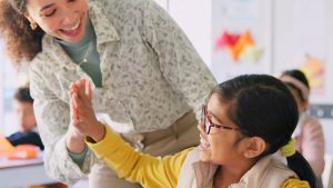 A teacher and a student high fiving.
