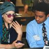 An adult showing their mobile phone to a teenage student.