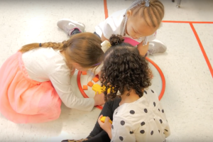 An overhead view of three preschool students playing with anagrams.