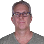 Middle aged white man with short gray hair wearing glasses and a v-neck sage colored shirt
