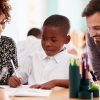 Two adults working with a young student.