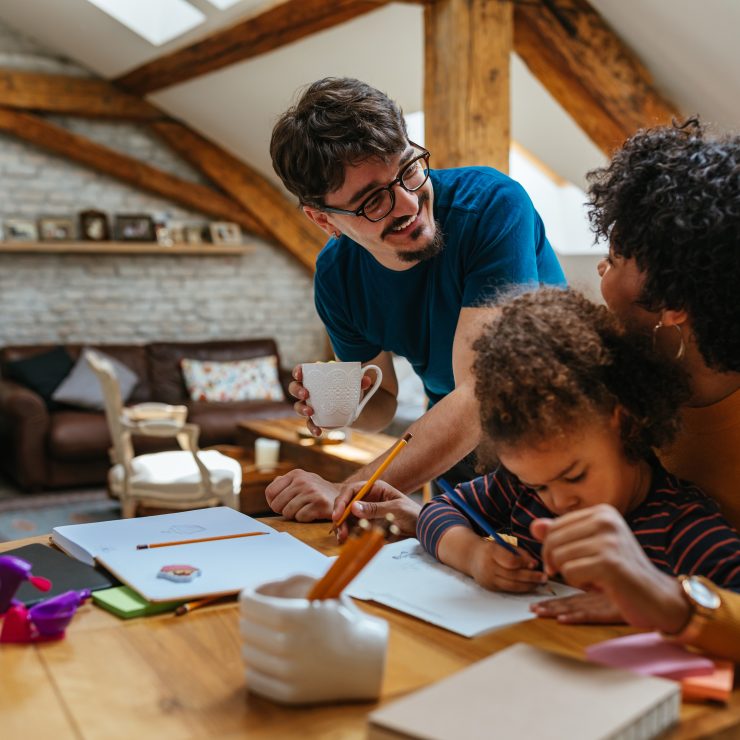 Two parents helping their child to learn draw.