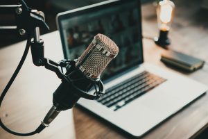 Home studio podcast interior. Microphone, laptop and on air lamp on the table, close-up
