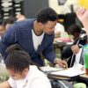 An adult helping a child in a classroom.