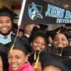 People in graduation regalia holding a flag that says, "Johns Hopkins University."