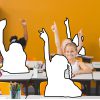 Children in a classroom raising their hands; some are outlines.