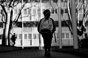 Black and white image of a child wearing a backpack.