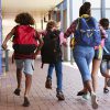 Children with backpacks running.