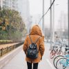 A person wearing a backpacking walking on a sidewalk.