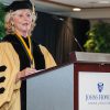 Allyson Handley speaking at a podium in graduation regalia.