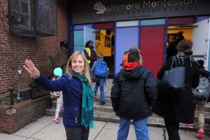 A person waving outside of the Baltimore Montessori Public Charter School.