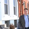 Steven B. Sheldon standing outside Baltimore rowhomes.