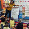 A teacher and young students in a classroom.