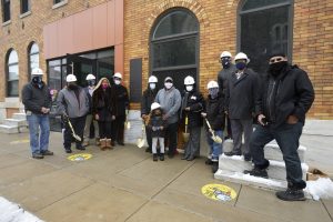 A group of people in masks and hardhats standing outside posing for a photo.