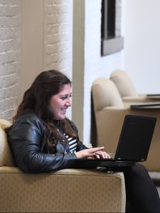 A person smiling while working on a laptop.