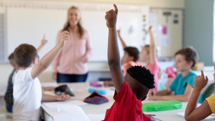 Children raising their hands in a classroom.