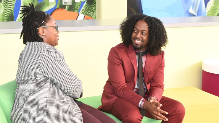 Two people sitting, talking, and smiling.