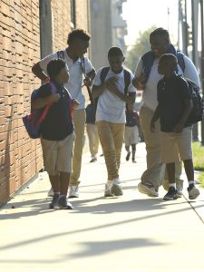 Young students walking on a sidewalk and smiling.
