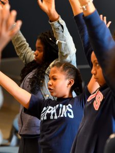 Children stretching their arms to the ceiling.