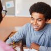 A teenage student smiling in a classroom.