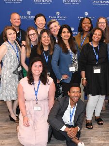 Johns Hopkins EdD students posing in front of a Johns Hopkins School of Education banner.