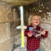 A young boy standing inside a cement structure holding a book