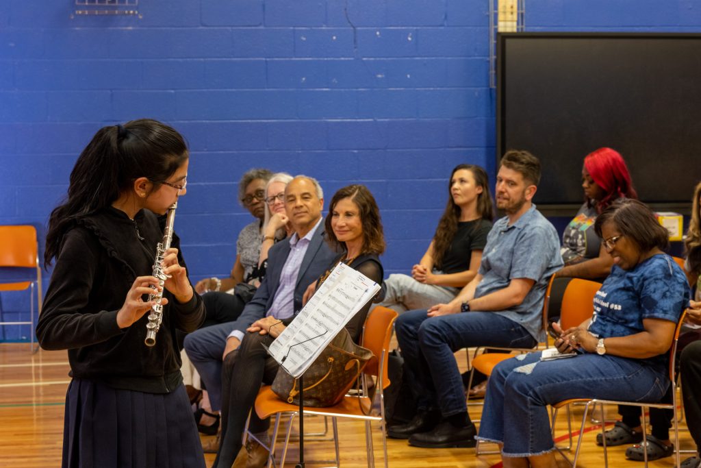 Girl playing the flute in front of a crowd.