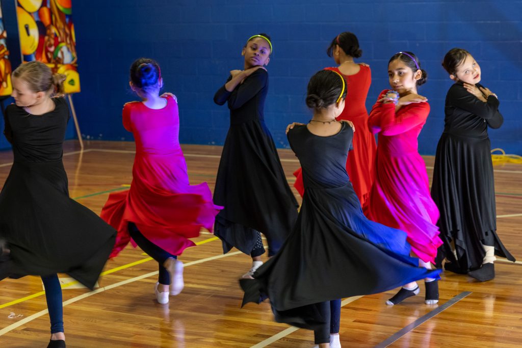 Young girls dancing in black and pink dresses.