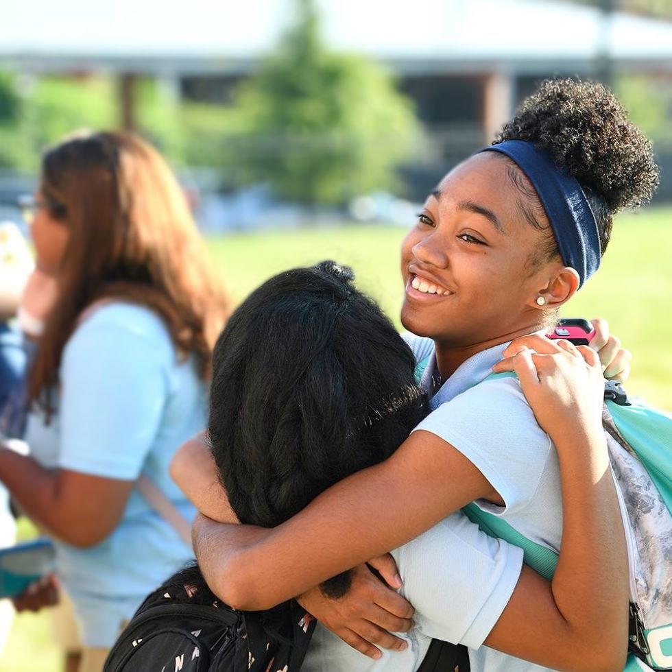 Two school children hugging.