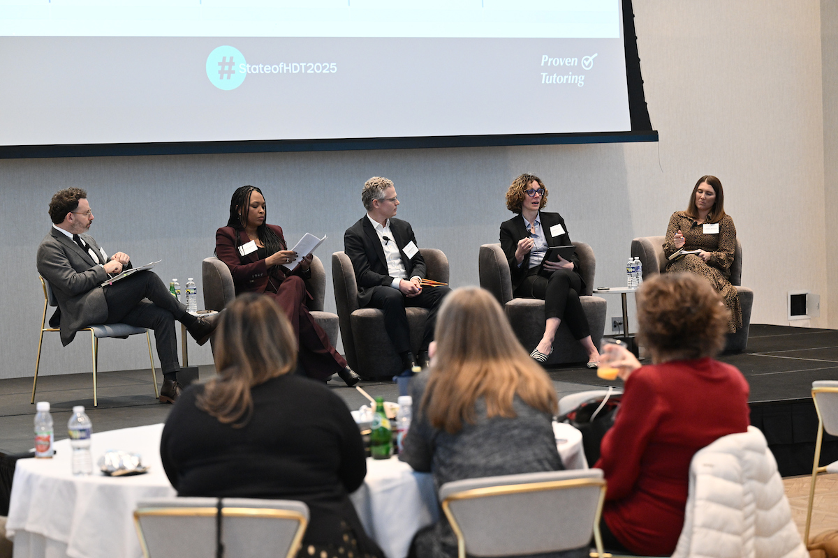 Five people sitting on a stage during a panel session.