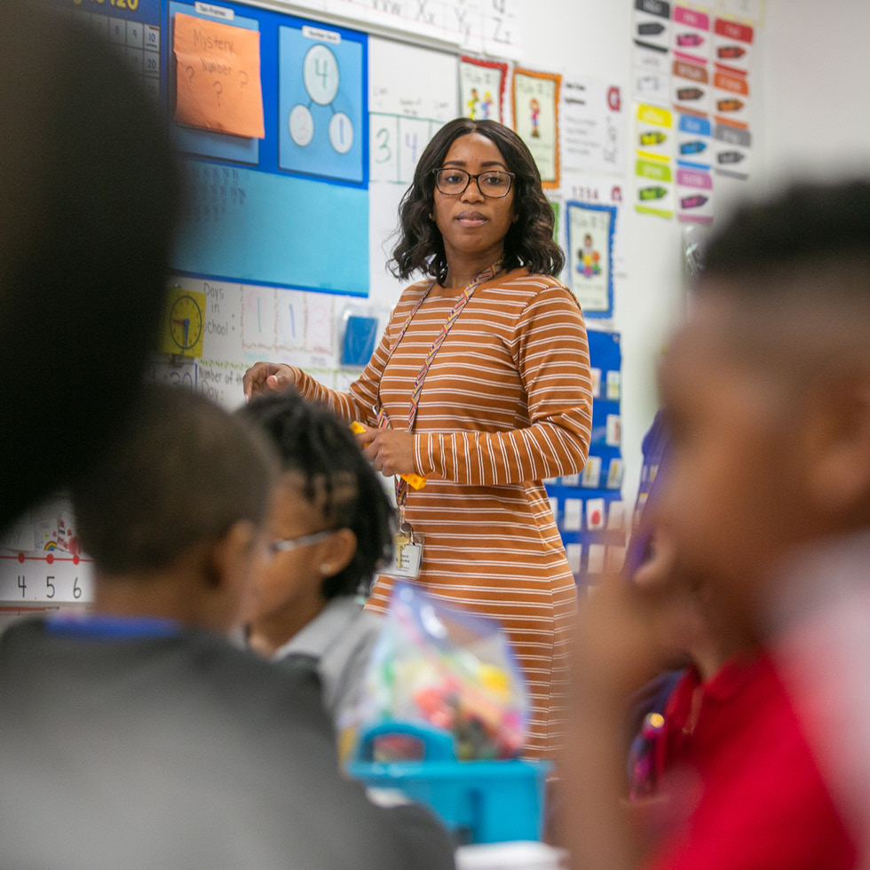 A teacher standing at a board in front of a grade school class.