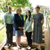 Four people standing on brick steps outside under a tree.