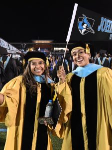 Two doctoral Graduates wave Johns Hopkins Pennants after Graduation