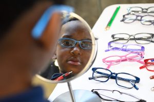A child looking in a mirror at their new eyeglasses.