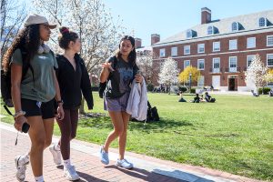 three students walk across Homewood campus as the trees bloom in spring