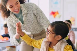 A teacher and a student high fiving.
