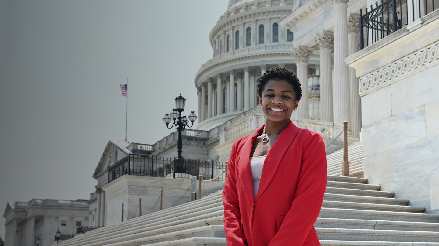 an education policy student stands in front of the United States Capitol building