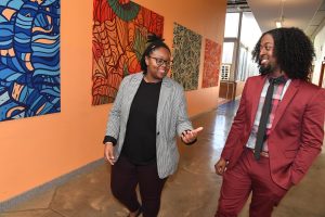 Two people walking in a hallway of a school engaging in conversation