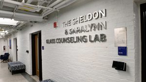 A wall with lettering that says "The Sheldon and Saralynn Glass Counseling Lab"