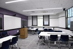 A classroom with a large whiteboard and several tables and chairs