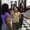 Three people standing in a hallway smiling and talking