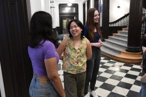 Three people standing in a hallway smiling and talking