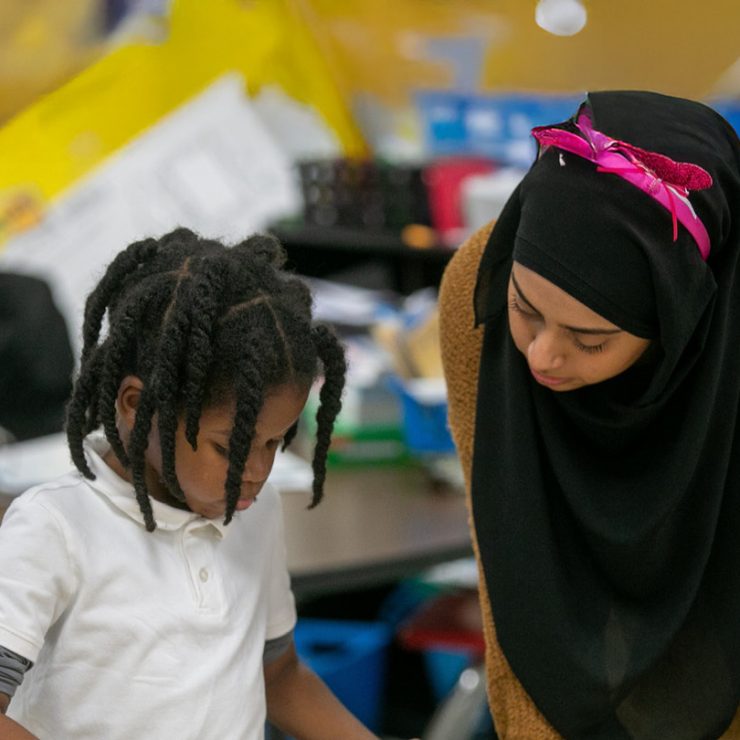 A teacher and a student looking at something together on a table