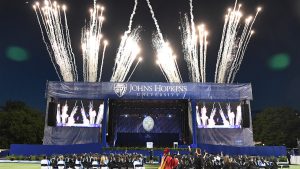 Fireworks light up the sky behind the Johns Hopkins graduation stage